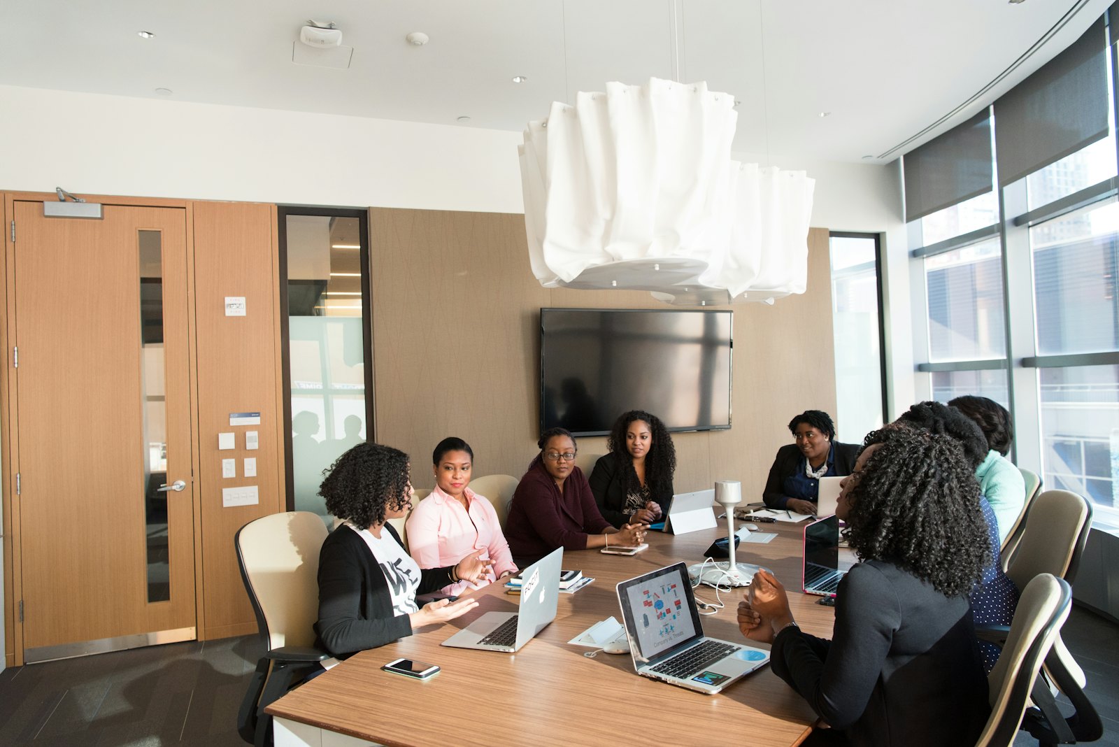 A team of Black women professionals in discussion around a boardroom table
